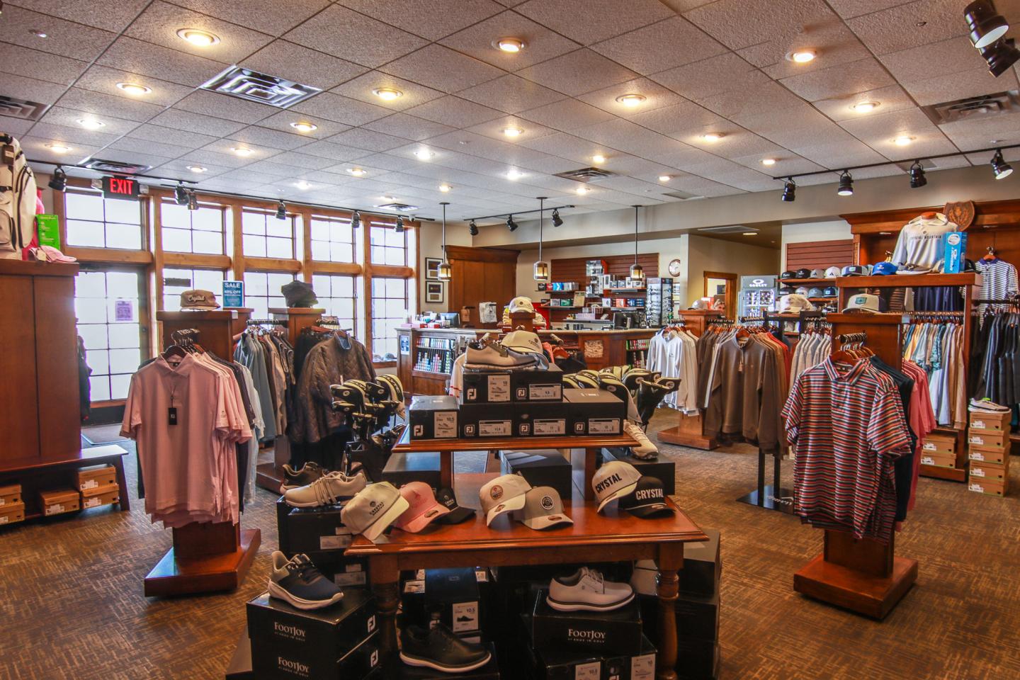 Clothing store interior with racks of shirts and shoes, warmly lit.