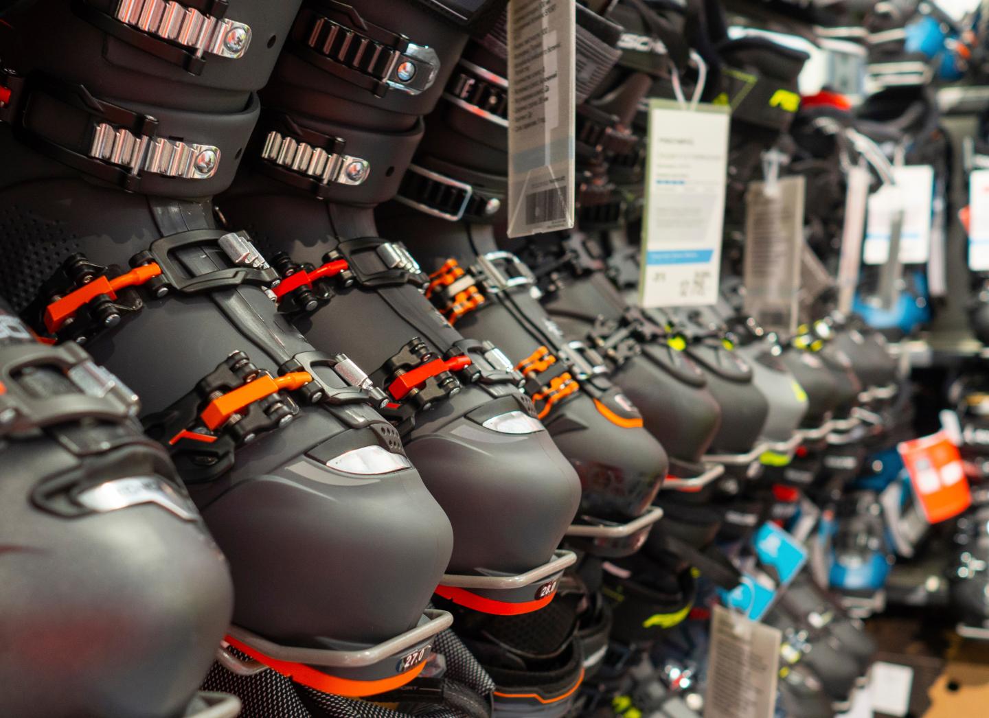 Row of ski boots with colored buckles displayed in a store.