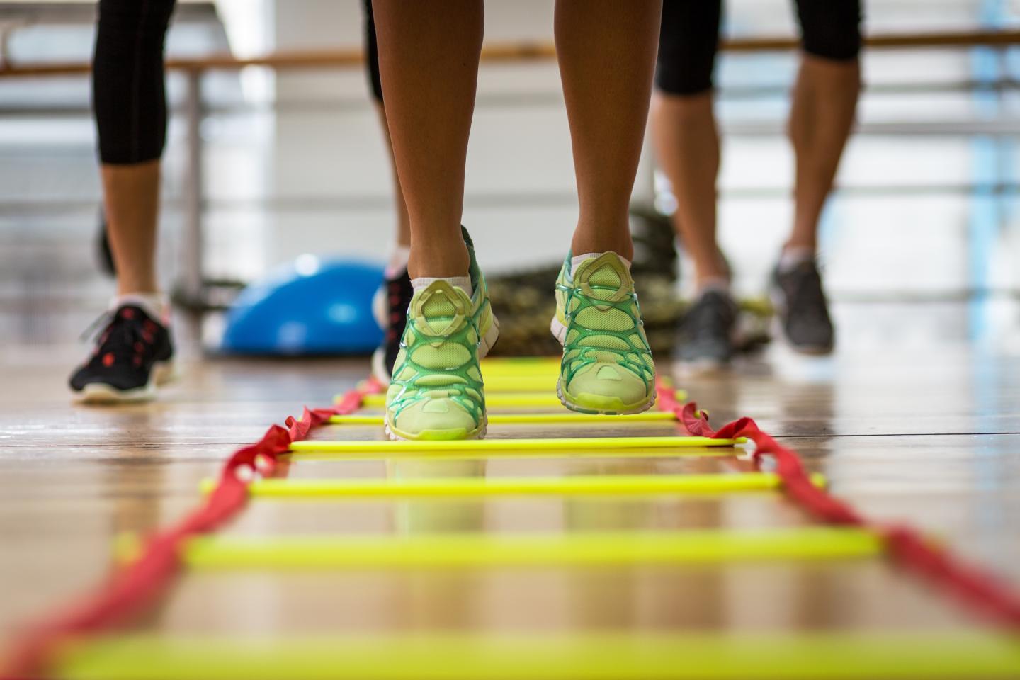 Bright sneakers on an agility ladder in a gym setting.