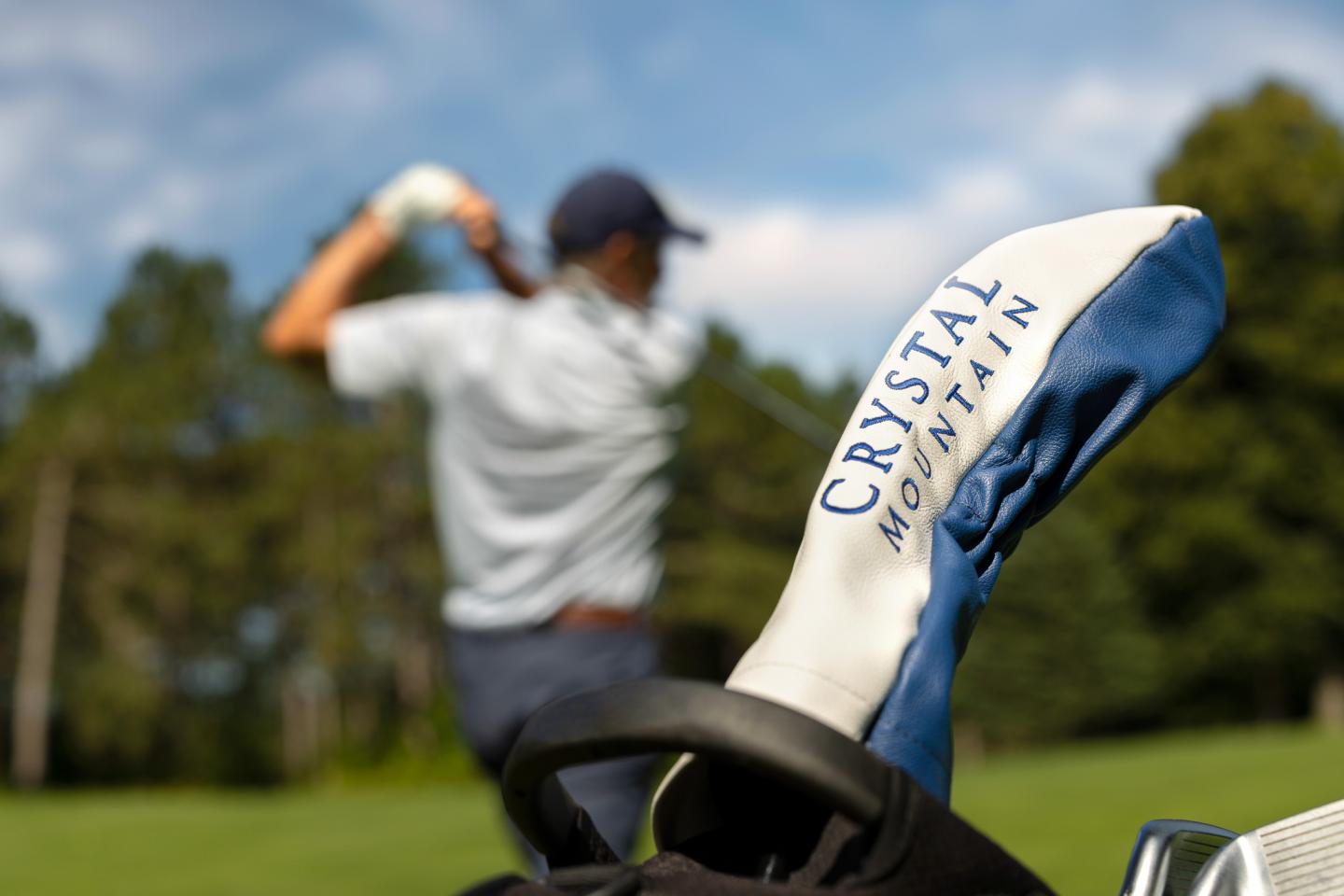 Golf club cover labeled "CRYSTAL MOUNTAIN," golfer swinging in blurred background.