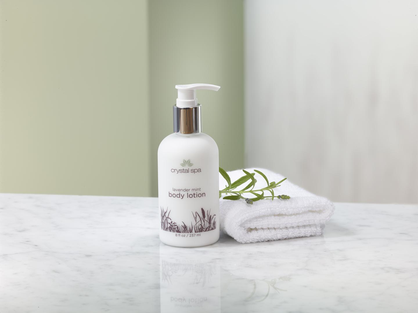 Crystal Spa body lotion bottle and towel on marble counter.