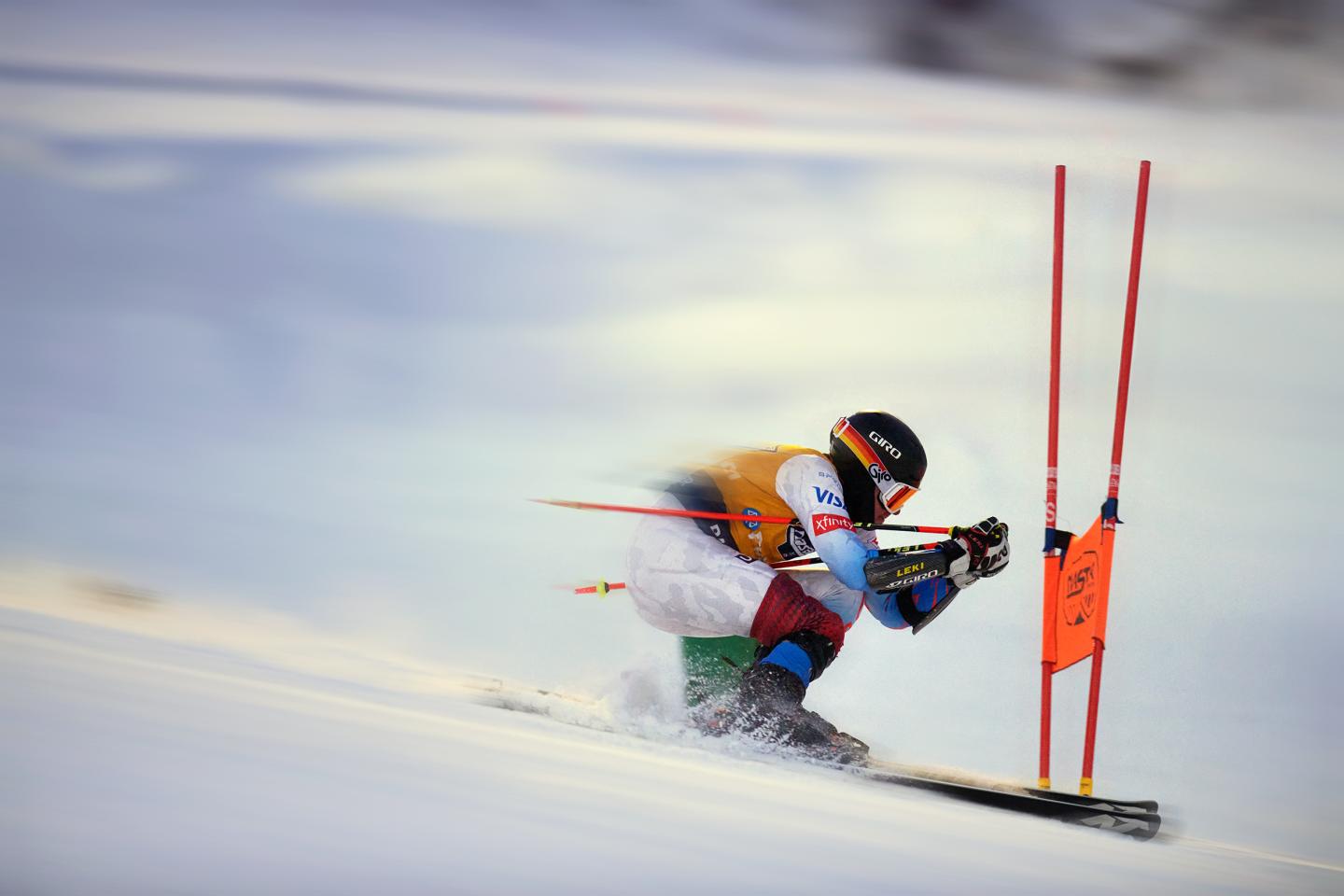 Skier racing downhill past red slalom gates.
