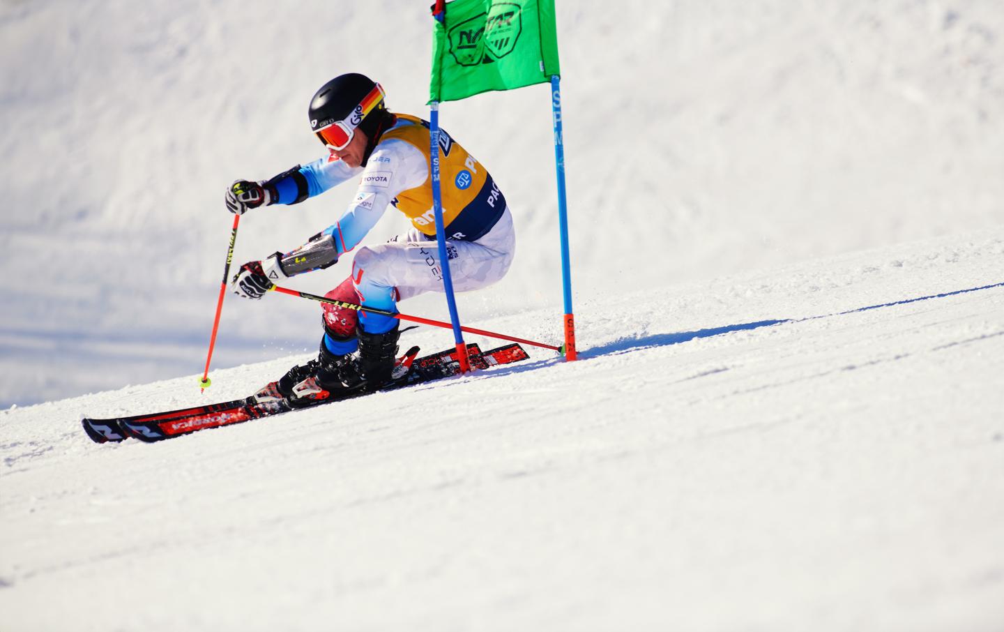 Skier in action on snowy slope, passing green flag.