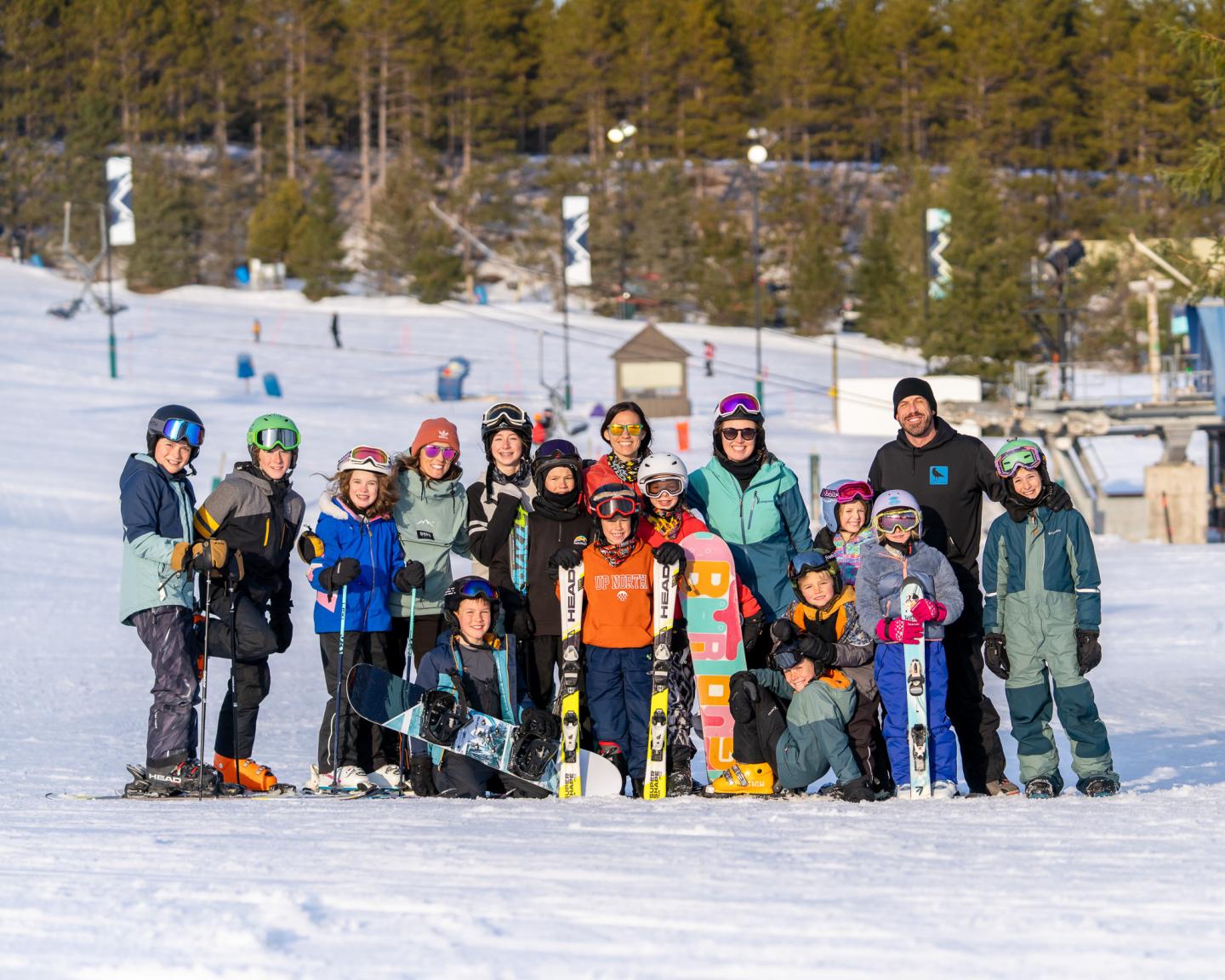 Group of skiers posing on a snowy slope with trees in the background.
