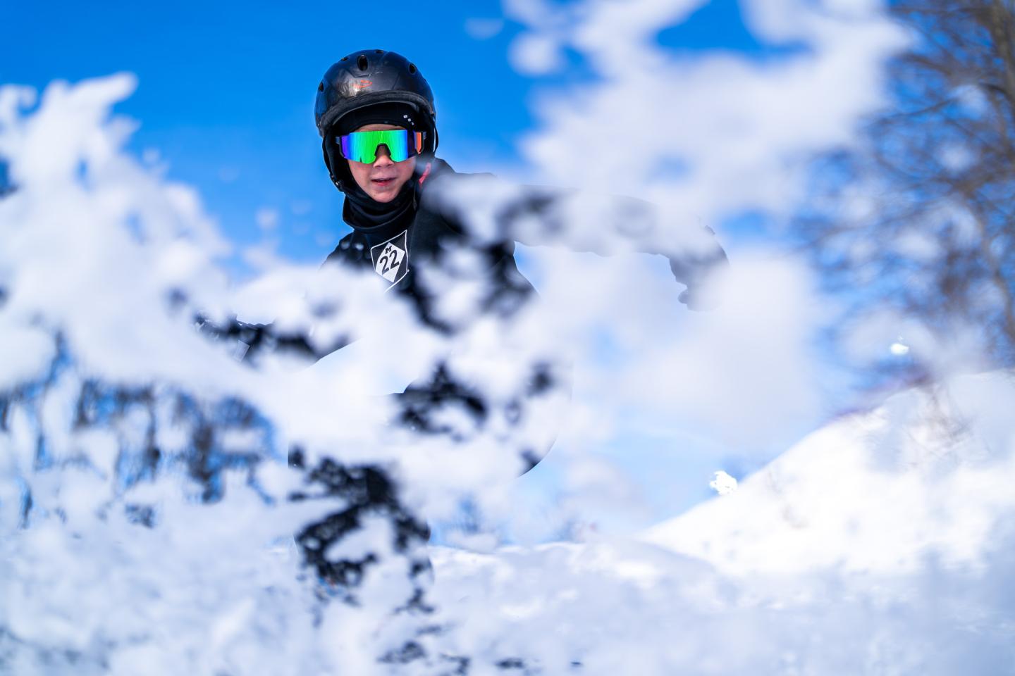 Snowboarder sprays snow mid-action, blue sky background.