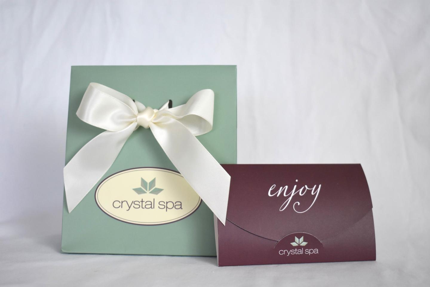 Gift bag with white ribbon, next to a maroon envelope.