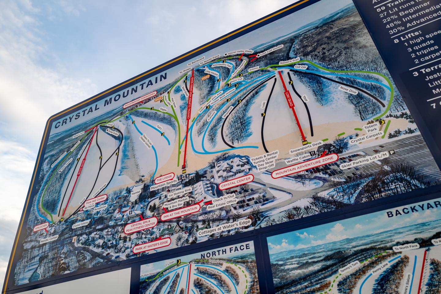 Ski trail map with colorful lines and labels under a blue sky.