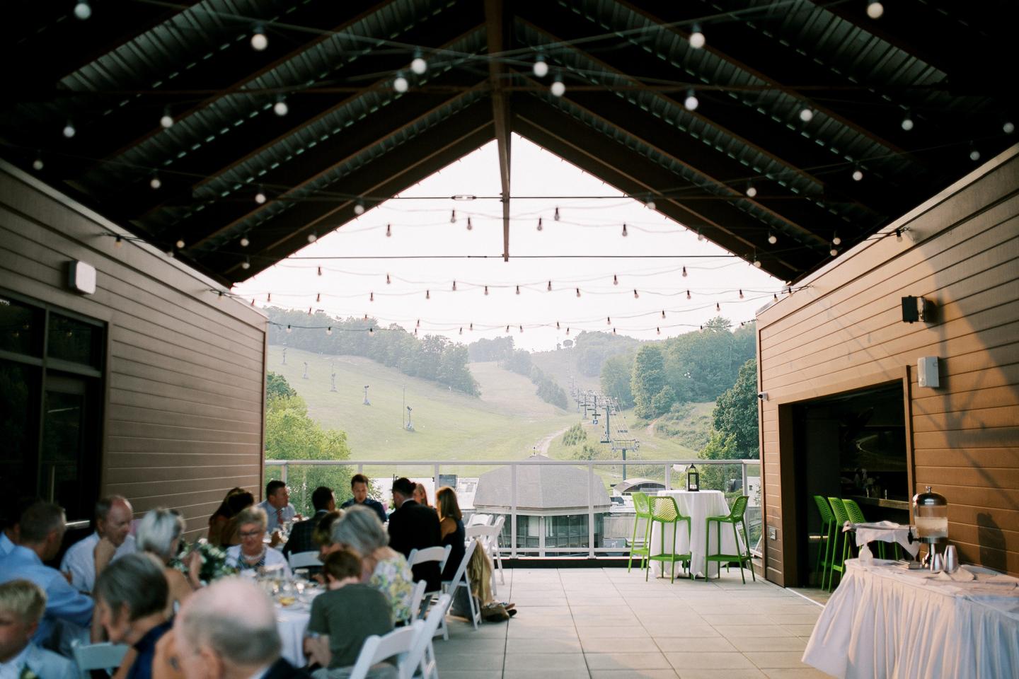 Outdoor dining area with string lights, overlooking a hillside view.