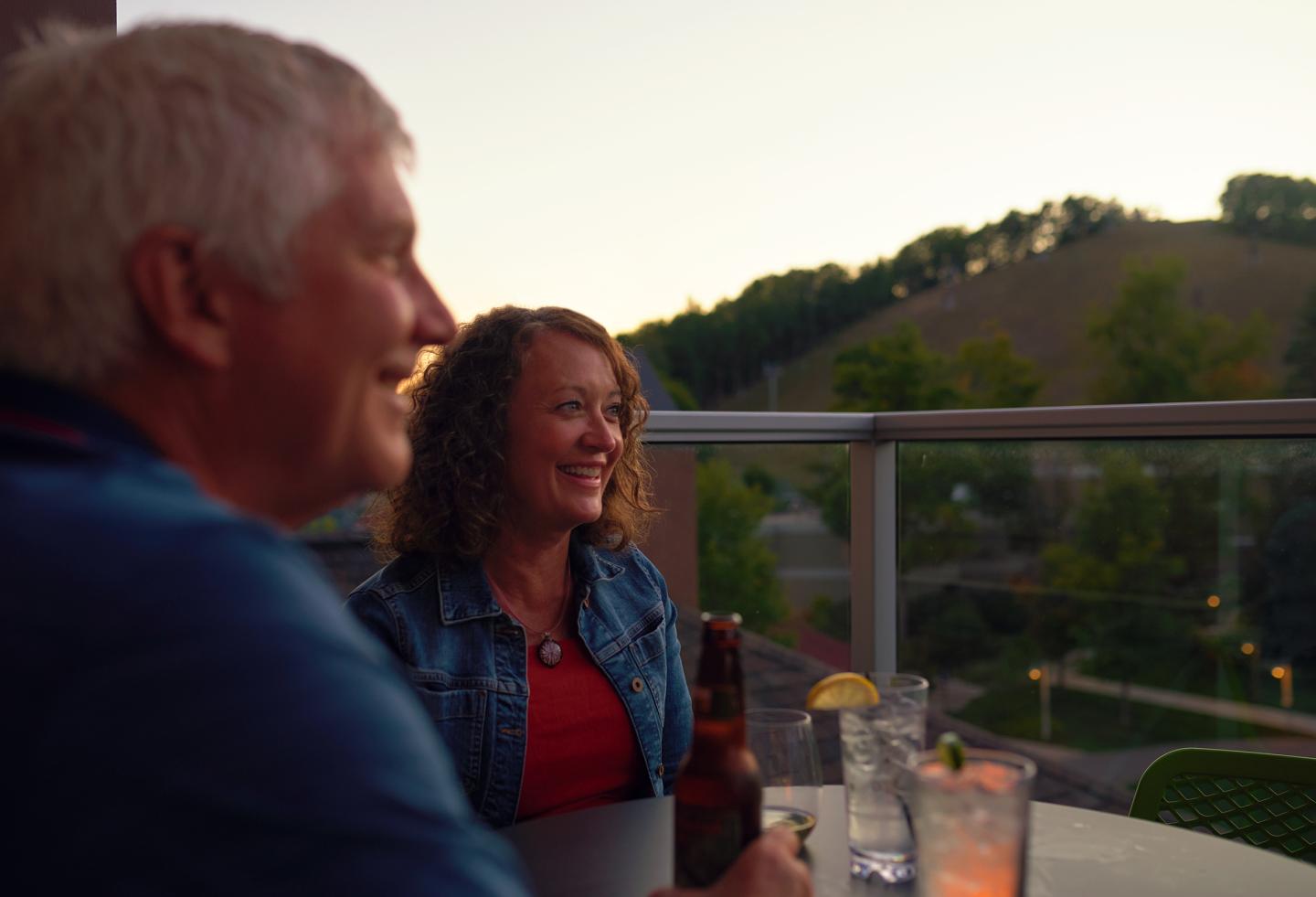 Adults smiling while drinking a beverage outdoors