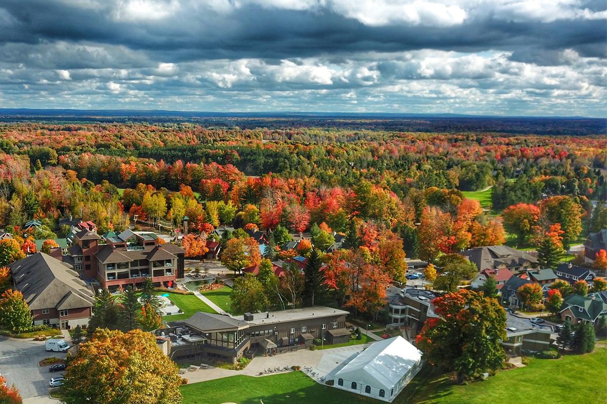 Aerial view of vibrant autumn trees surrounding Crystal Mountain under a cloudy sky.