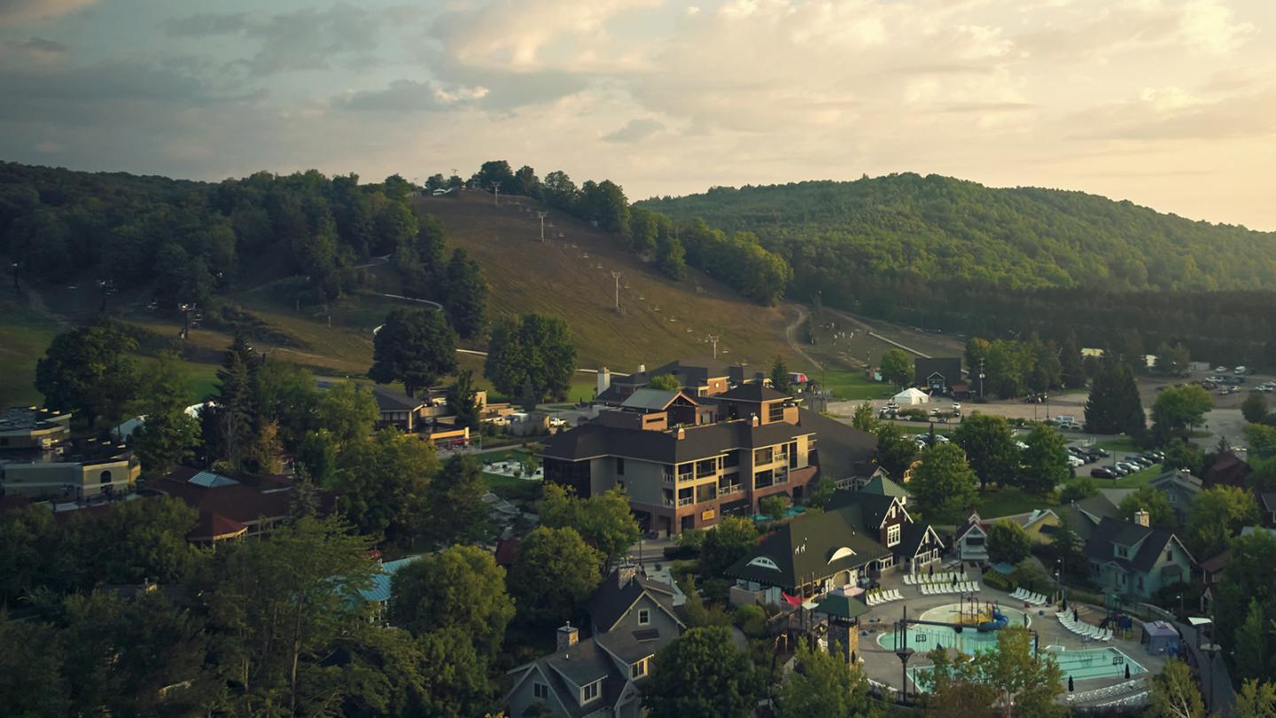 Resort surrounded by trees and hills at sunset.