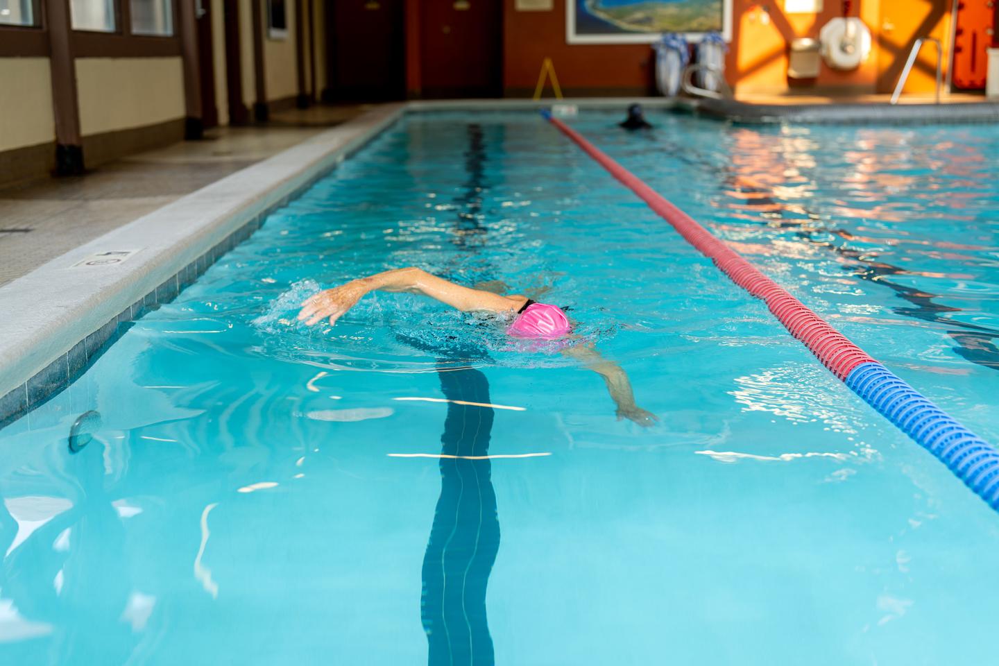 Swimmer in a pool with pink cap, performing freestyle stroke.