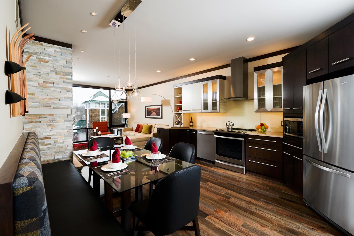 Modern kitchen with dining area, dark wood cabinets, stainless steel appliances.