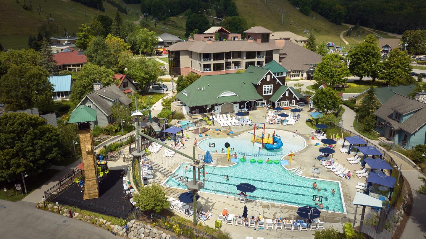 Aerial view of a resort pool, surrounded by buildings and trees.
