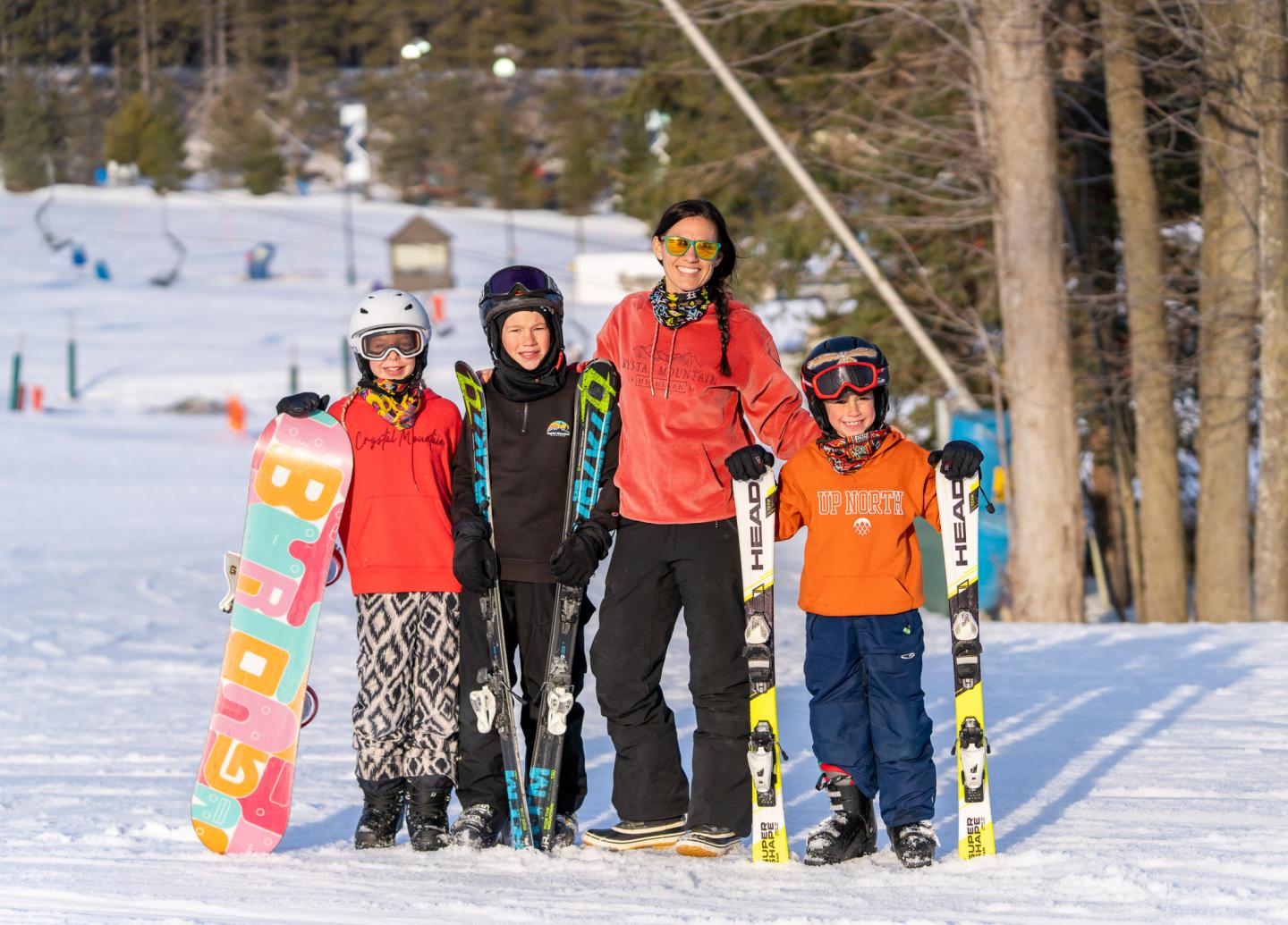 Family on snowy slope with ski gear, smiling.