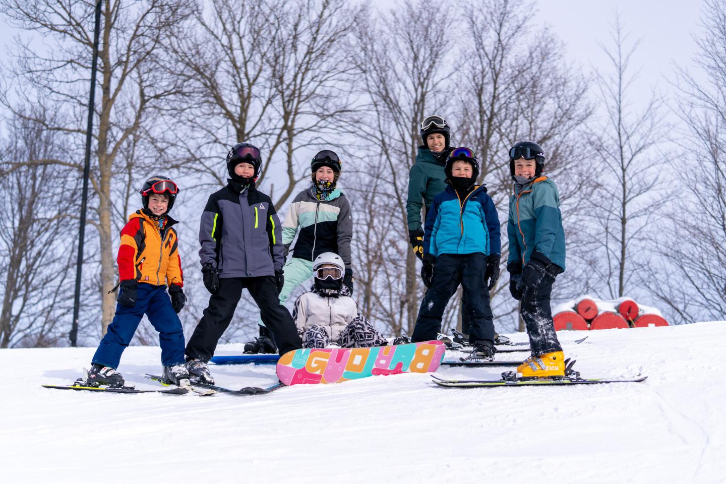 Group of skiers on a snowy slope, trees in the background.
