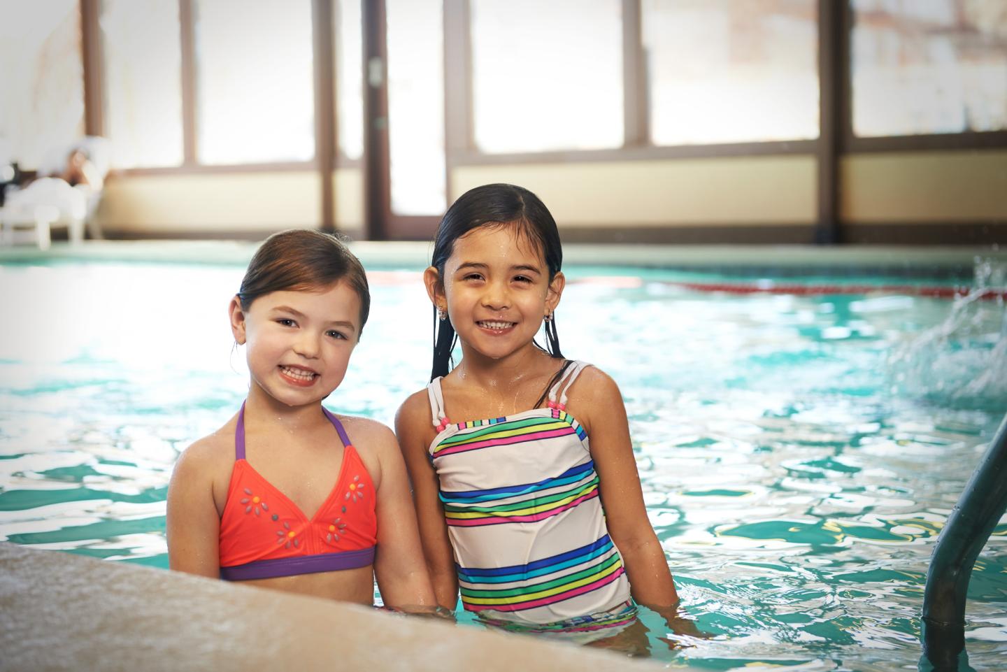 Two girls smiling in an indoor pool.