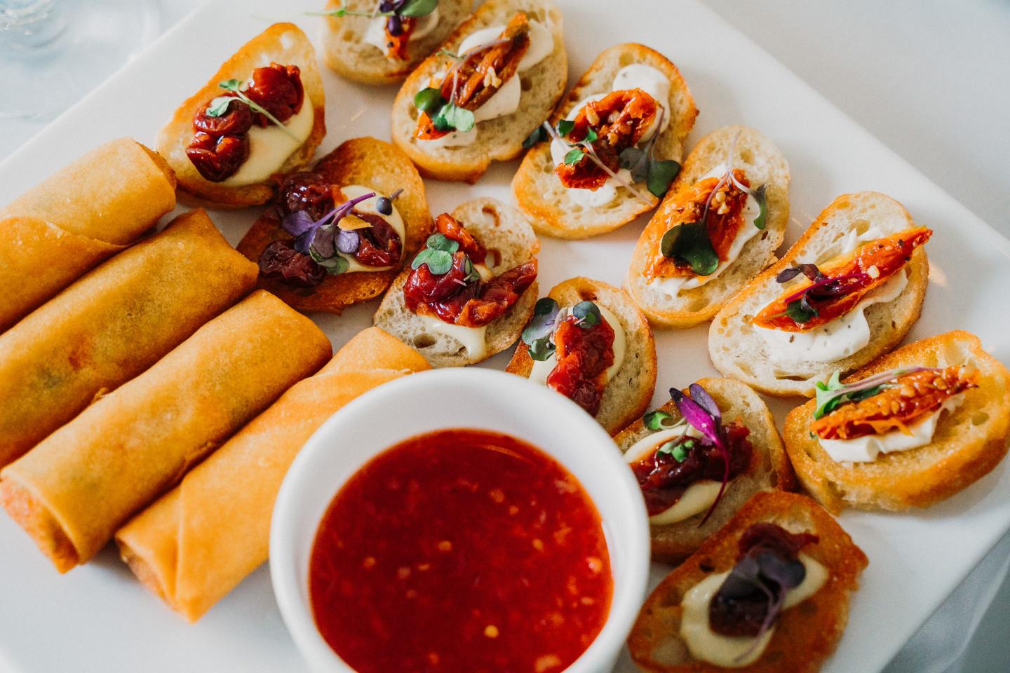 Spring rolls and bruschetta on a plate with dip.