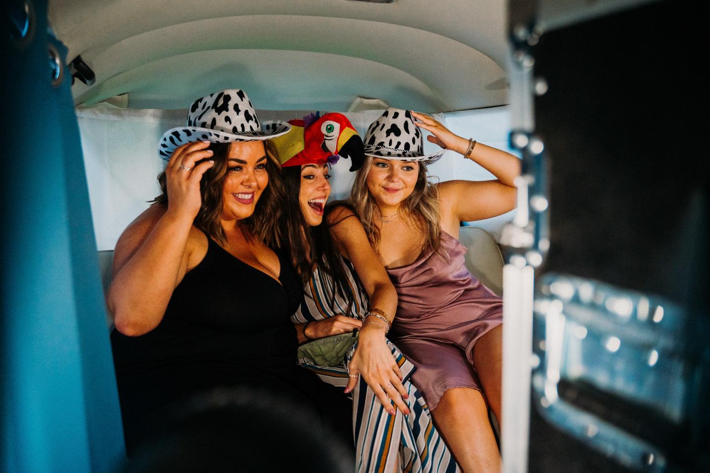 Three women in fun hats posing cheerfully in a photo booth.