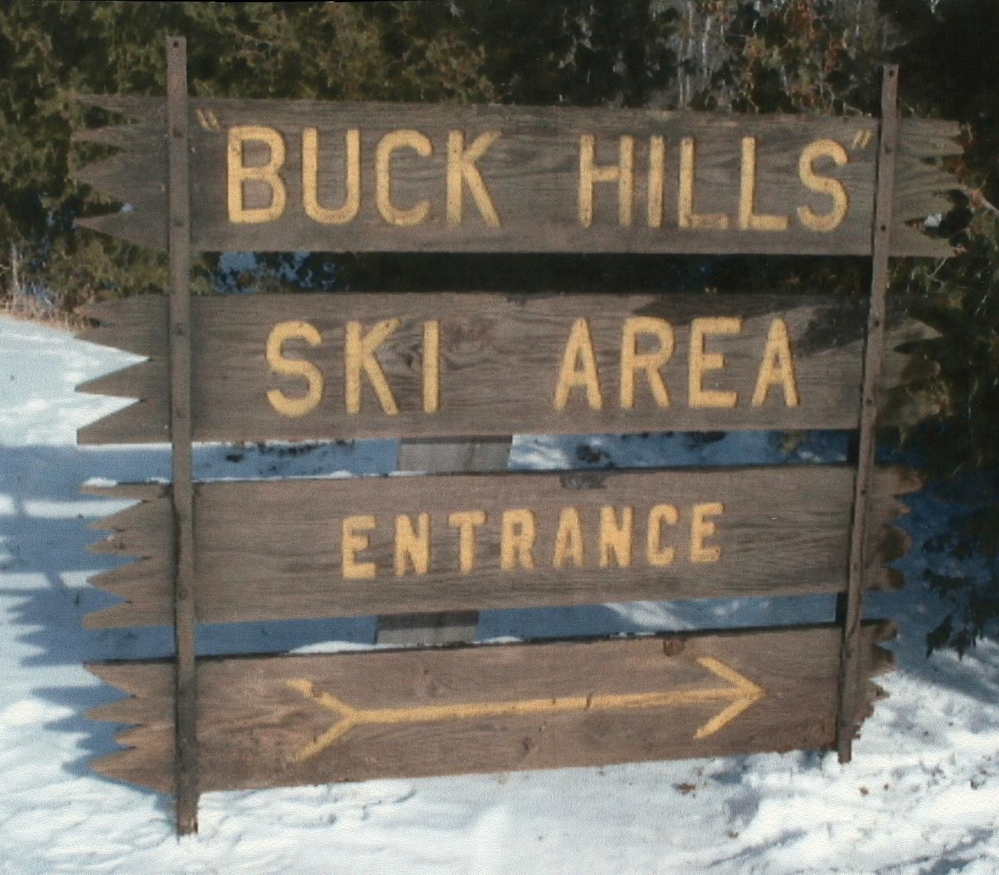 Wooden sign for Buck Hills Ski Area entrance, surrounded by snow.