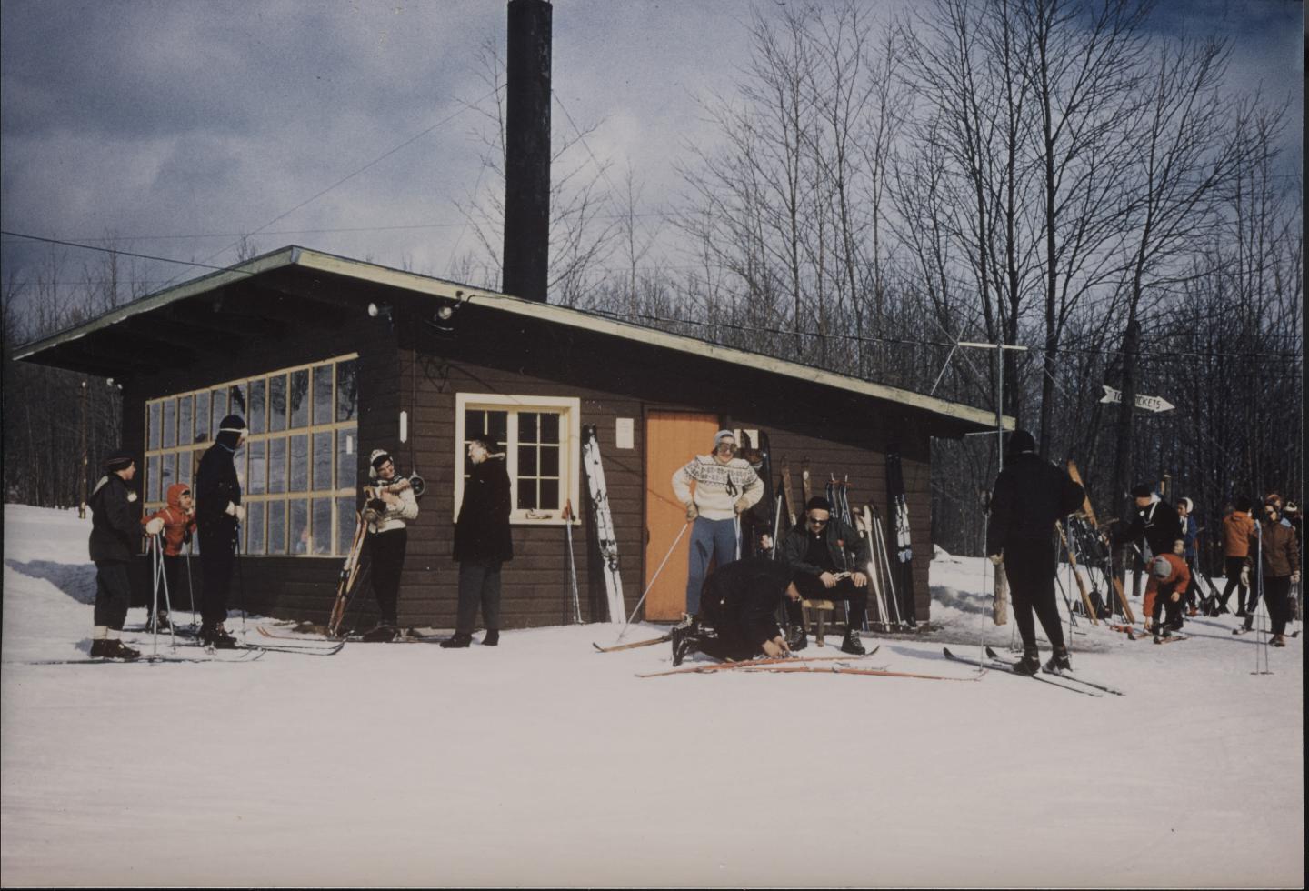 Skiers gather outside the warming hut on a snowy day.