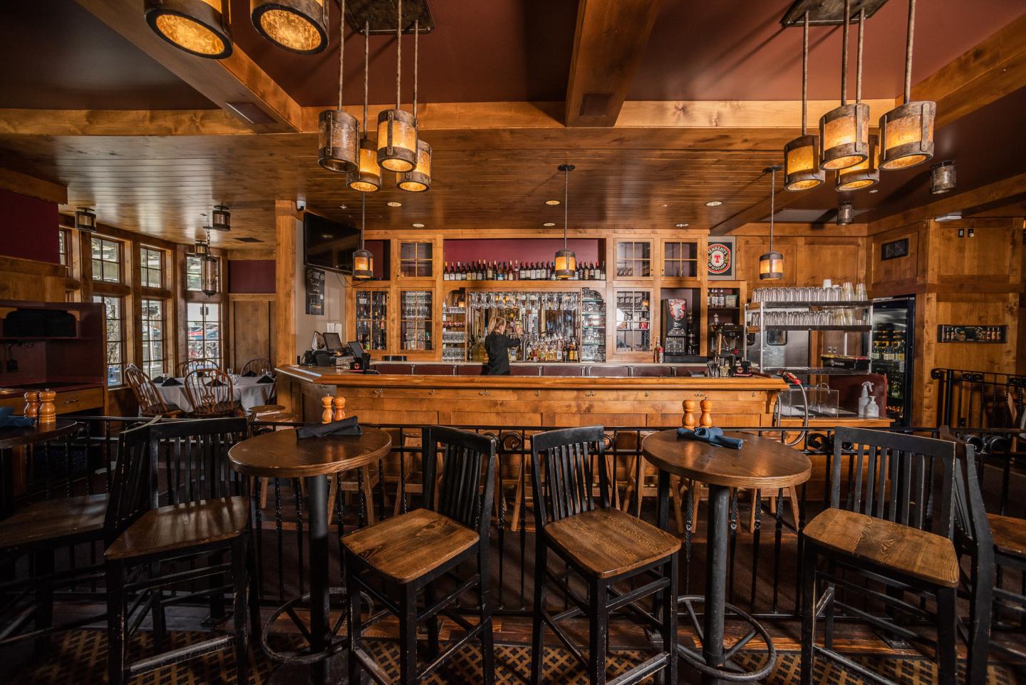 Cozy bar with wooden tables, chairs, and warm lighting.