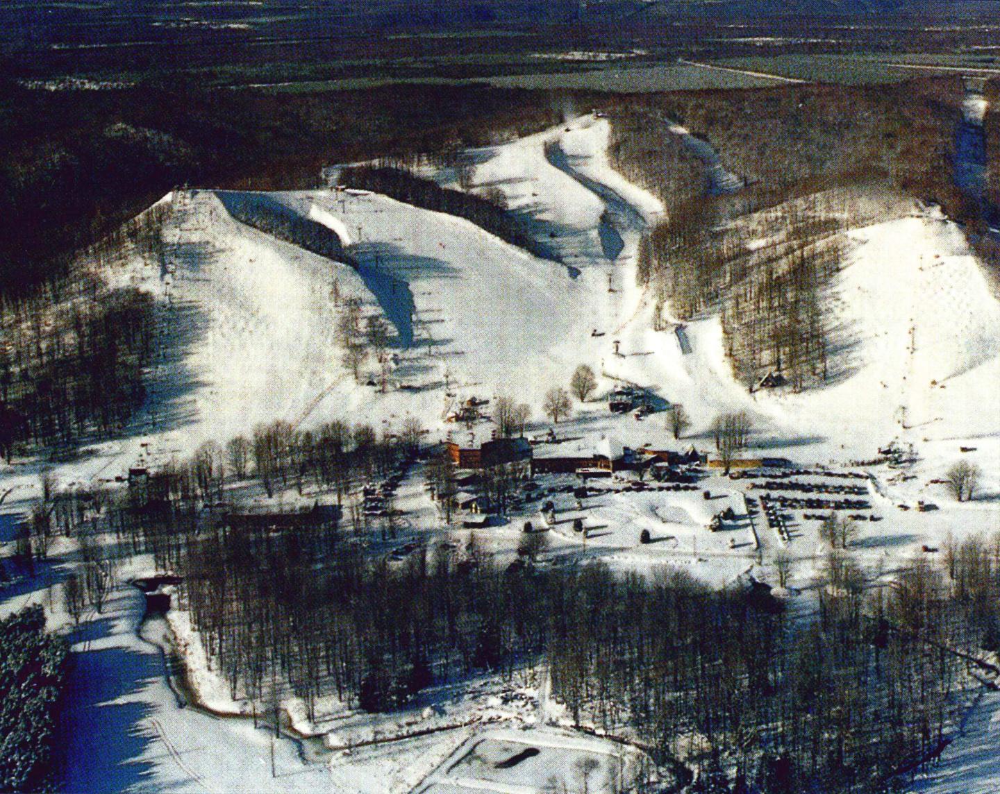 Snow-covered ski slopes surrounded by trees in a winter landscape.