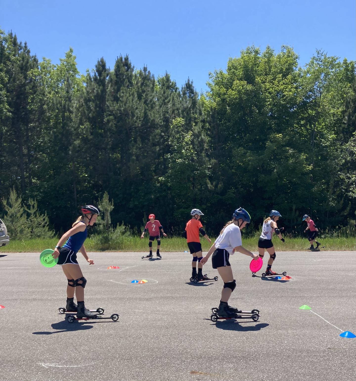 People roller skiing on a sunny day, wearing protective gear.