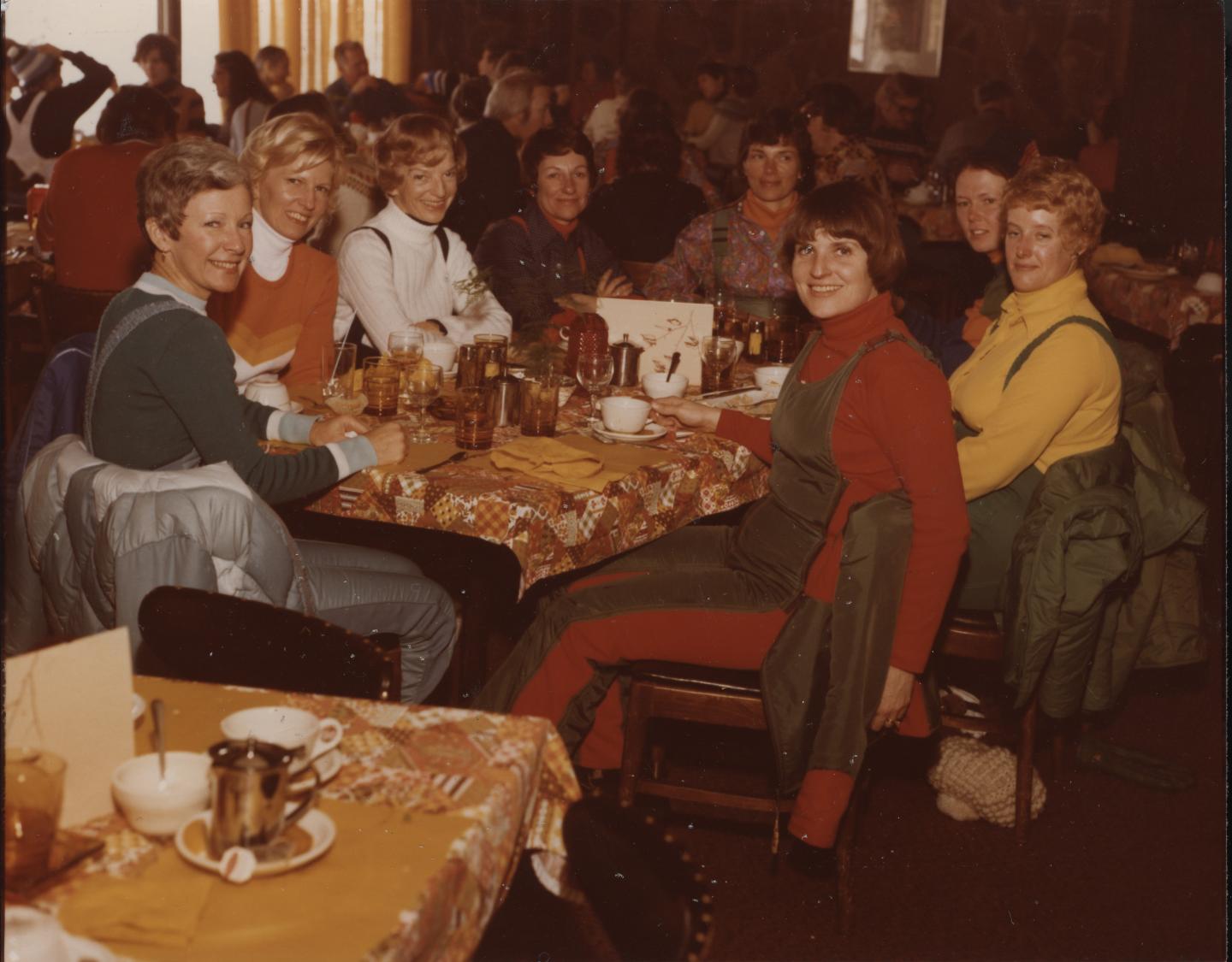Group of people seated at a restaurant table, smiling and enjoying their meal.