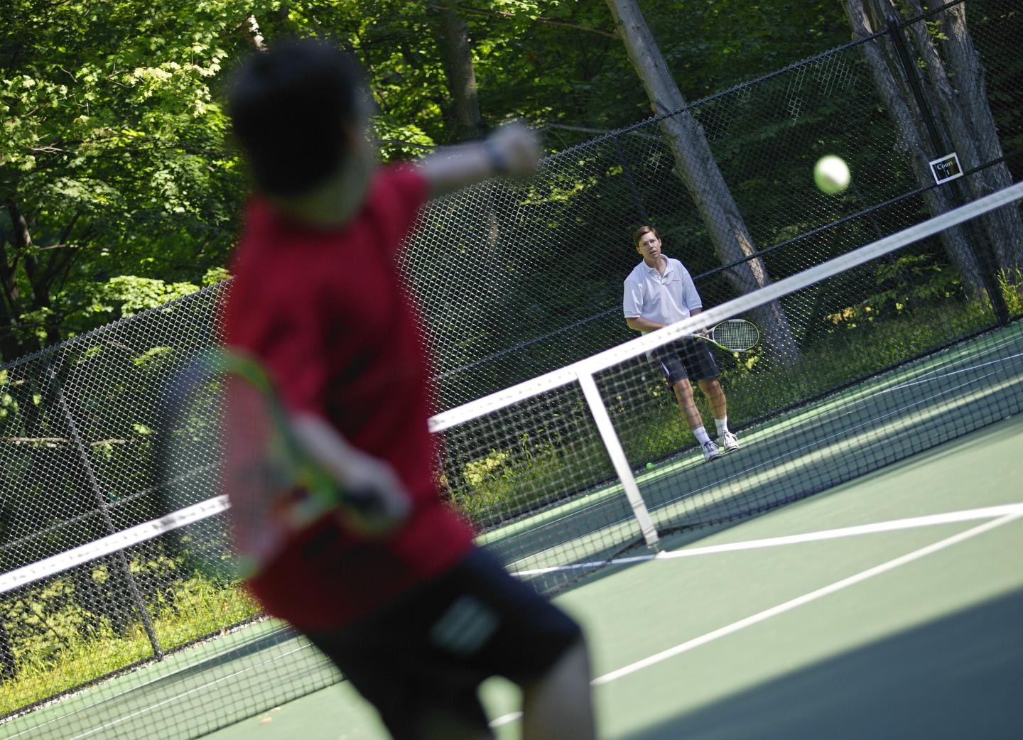 Tennis match with player serving on sunny outdoor court.