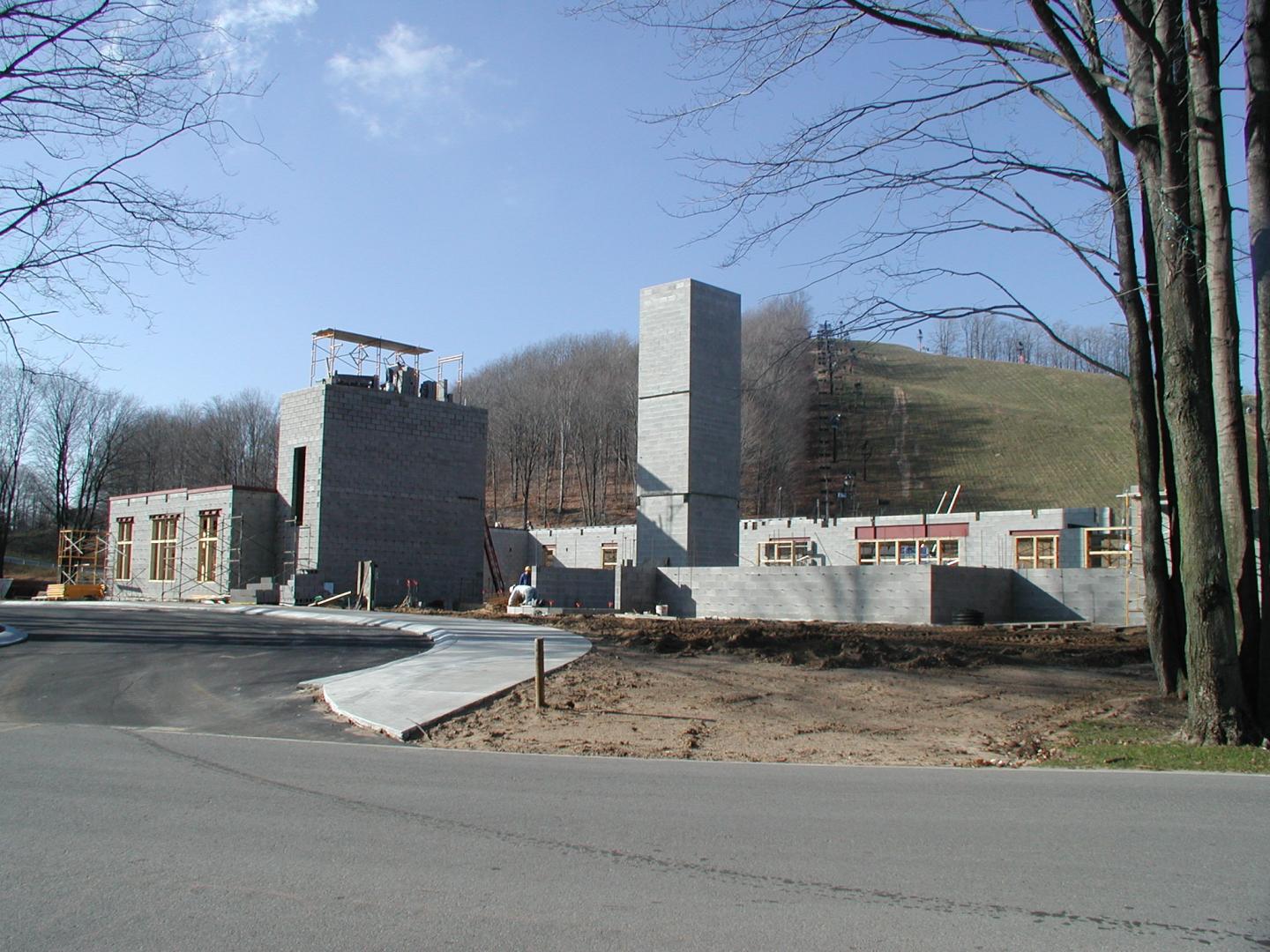 Construction site with concrete buildings and a scenic, hilly backdrop.