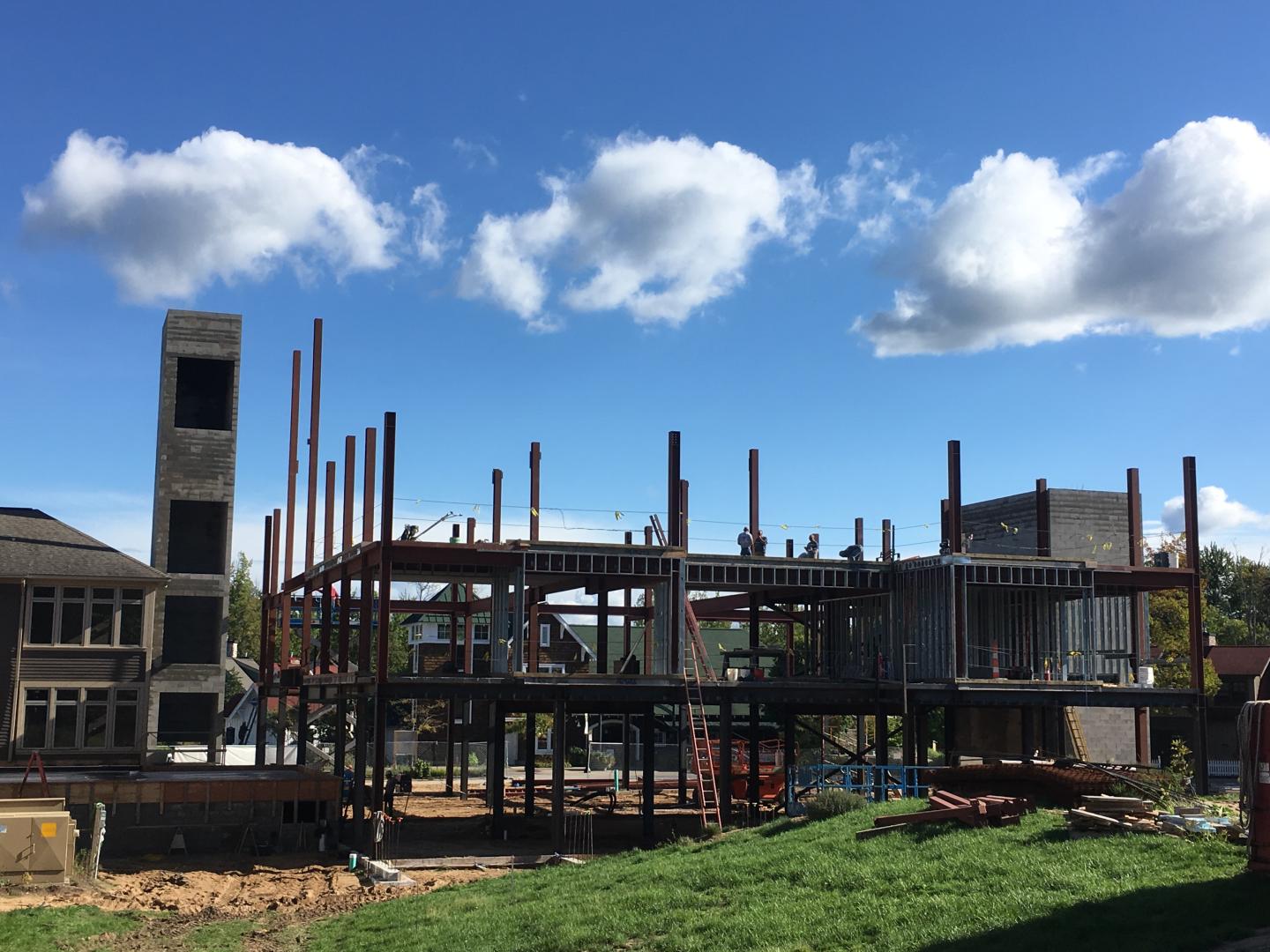 Construction site with steel beams under a blue sky with clouds.