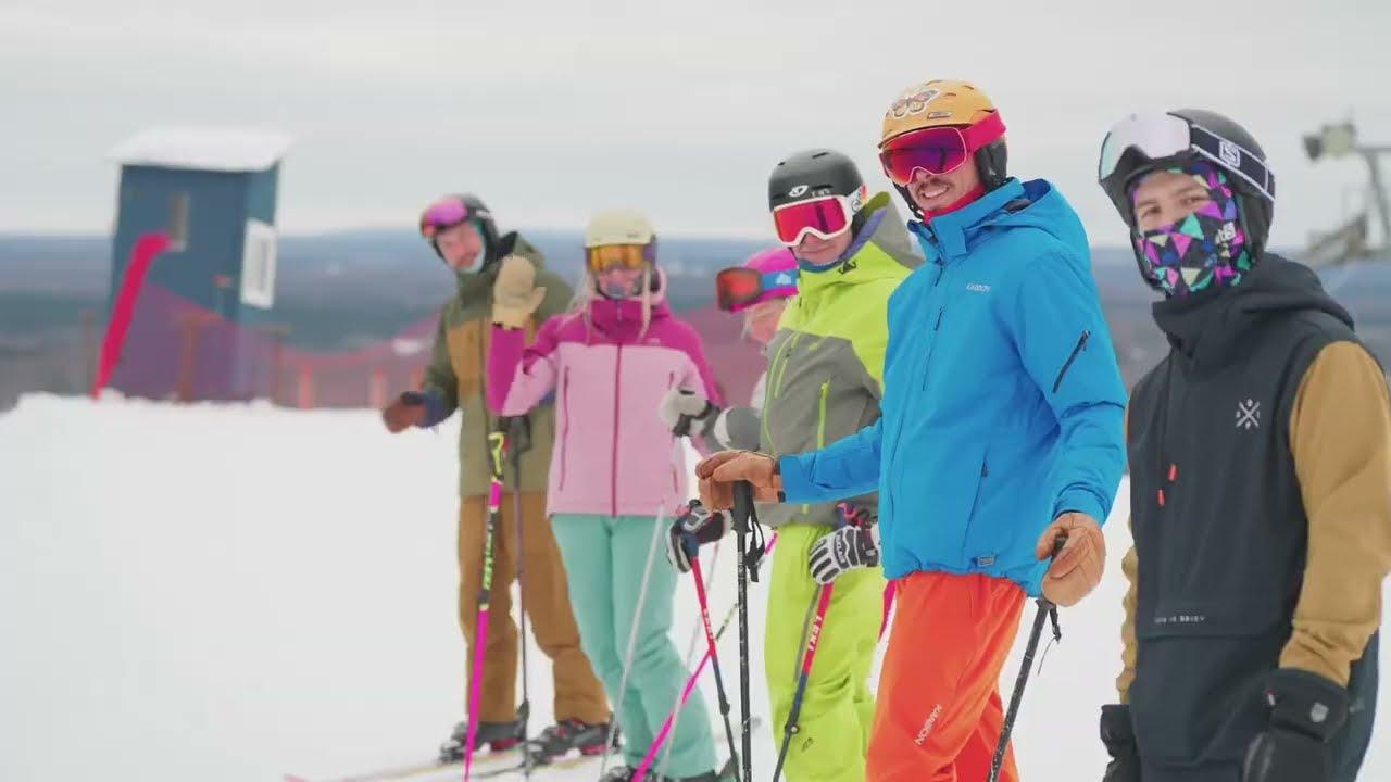 Skiers in colorful outfits standing in a snowy mountain setting.