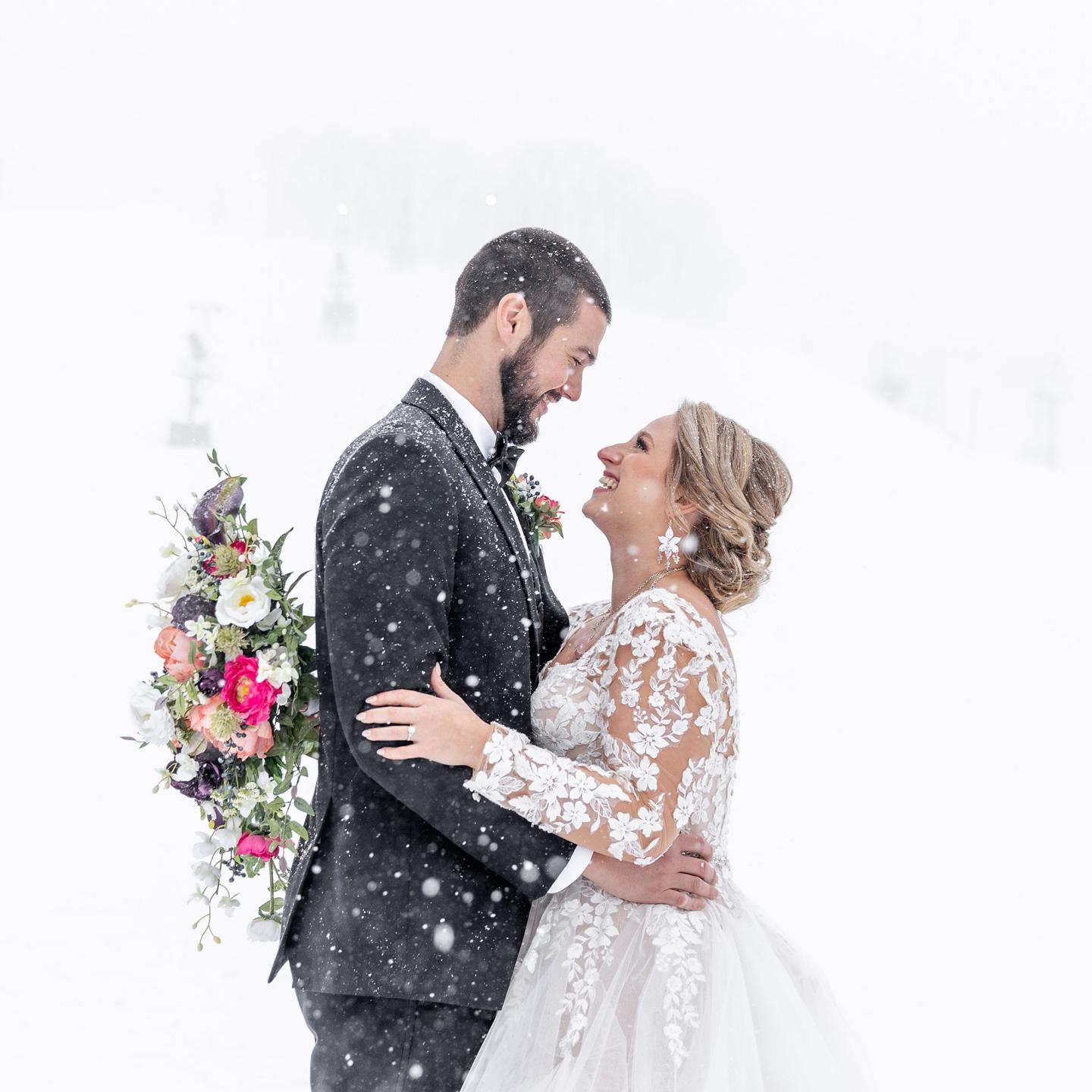 Happy couple embracing in snowy wedding setting.